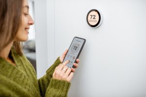 woman-uses-phone-to-change-smart-thermostat