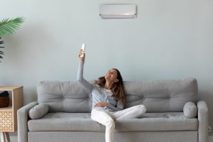 ductless-mini-split-woman-on-couch-controls-it